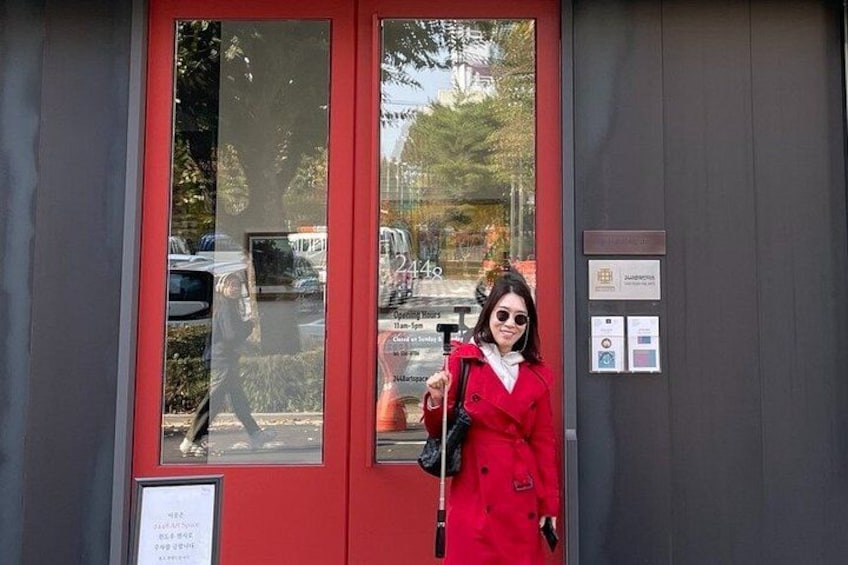 A red door with a glass panel, a person in a red coat holding a bag, and a sign with text. 3