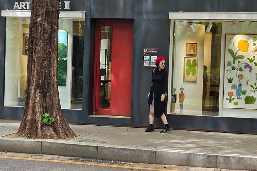 A tree, a storefront with a red door, and a person walking. 1
