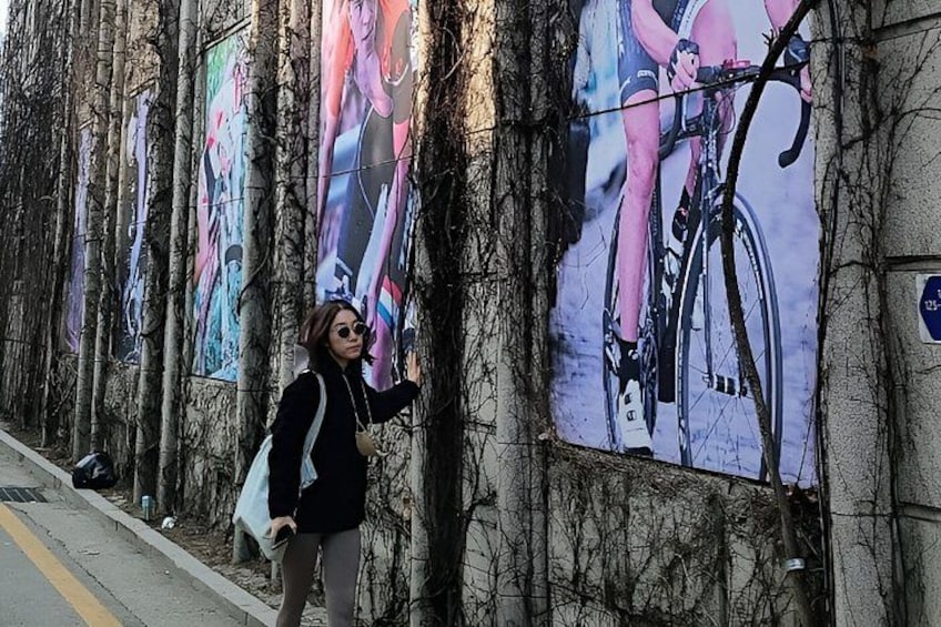 A person standing in front of a wall with large posters of cyclists. 5