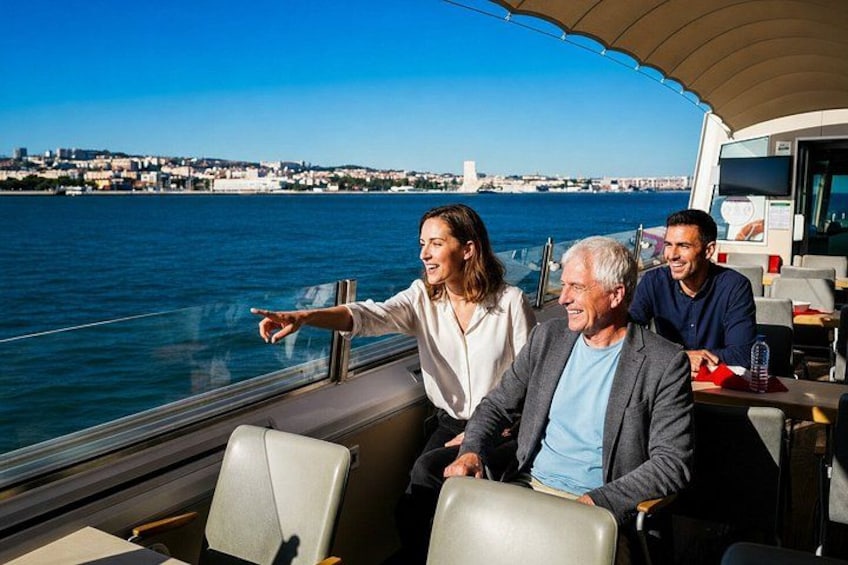 Un bote con tres personas, una señalando al agua, y un paisaje urbano al fondo. 2