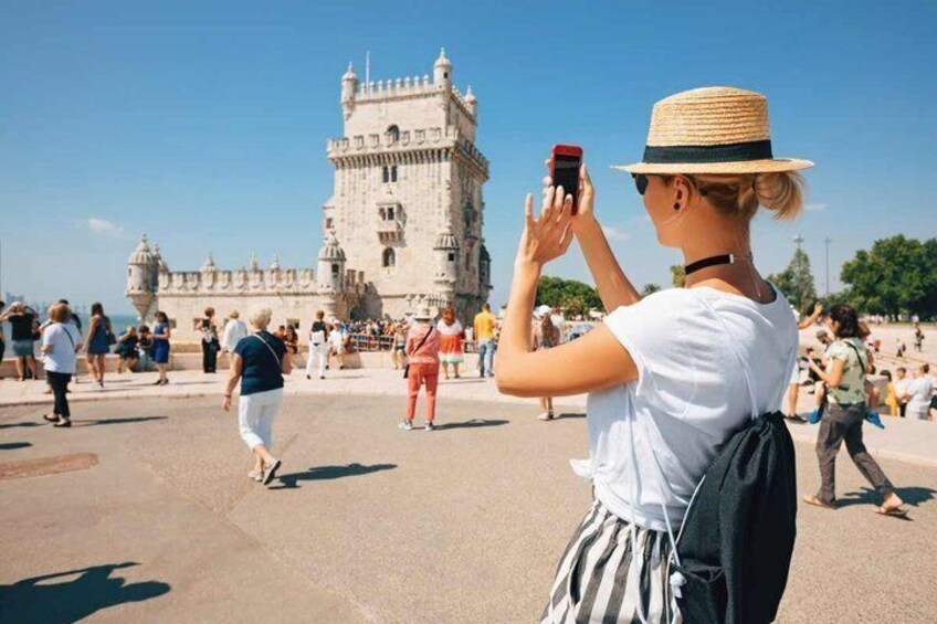 Una persona fotografiando una torre histórica con turistas de fondo. 1