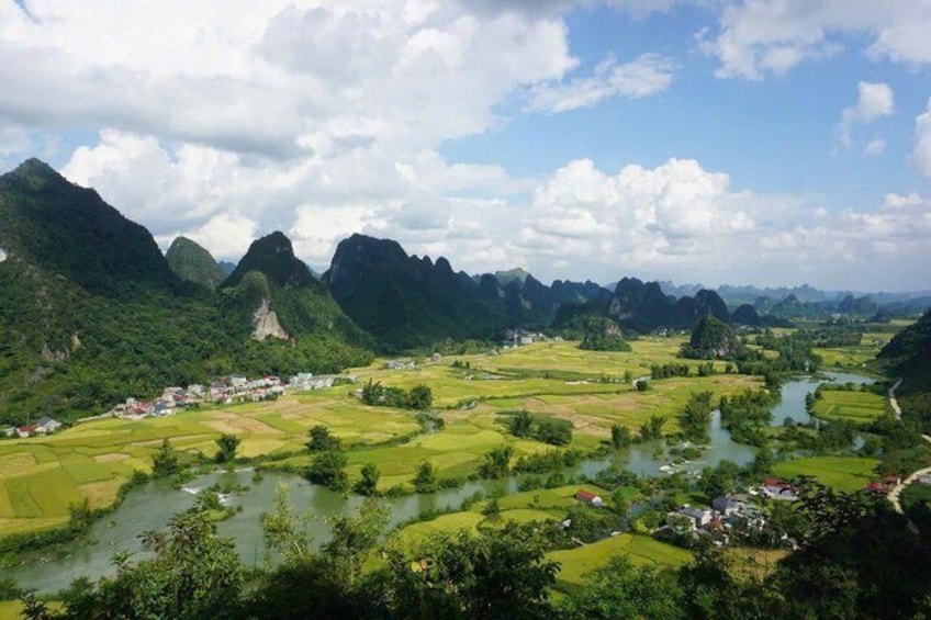 A river winding through terraced fields, surrounded by lush green hills and a small village. 4