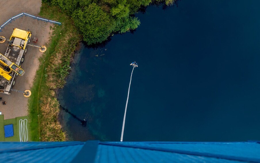 A zip line over a river with a boat dock and a yellow vehicle on the left. 4