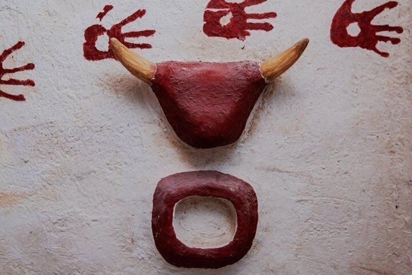 En skulptur af et oksehoved med horn og en rund fod på en muret væg. 2