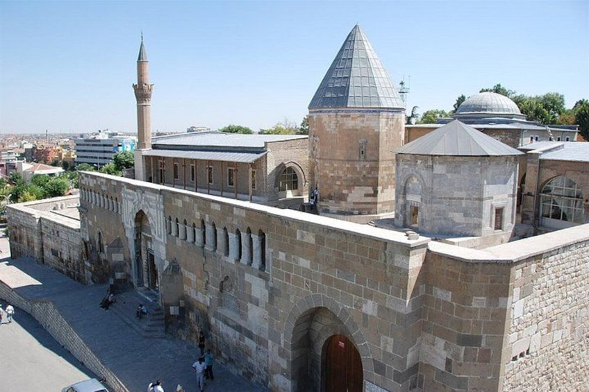 A historical building with a prominent minaret and dome, surrounded by a stone wall and a paved area. 2