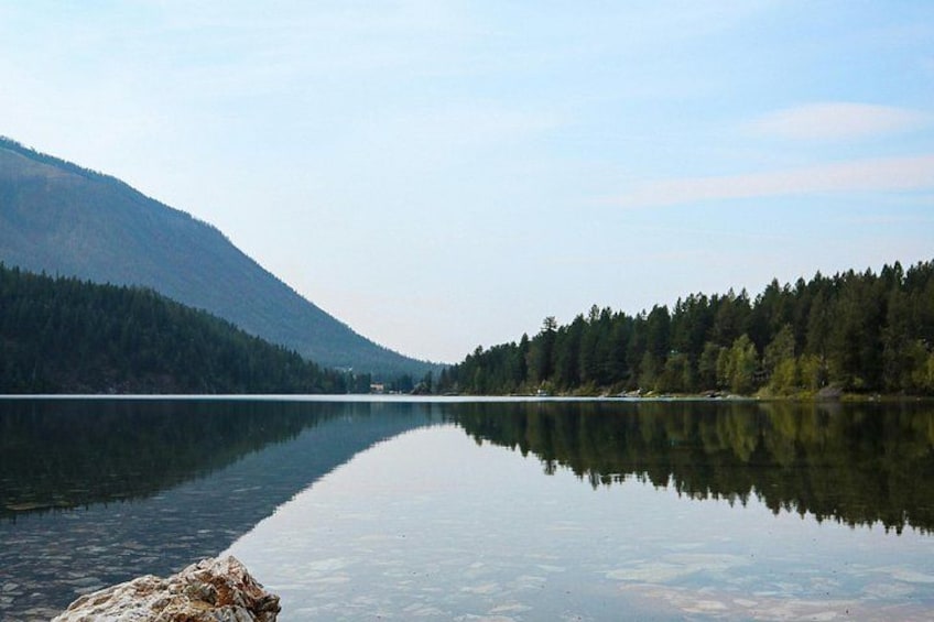 Ein ruhiger See mit einem Berg im Hintergrund und dichtem Wald am gegenüberliegenden Ufer. 4