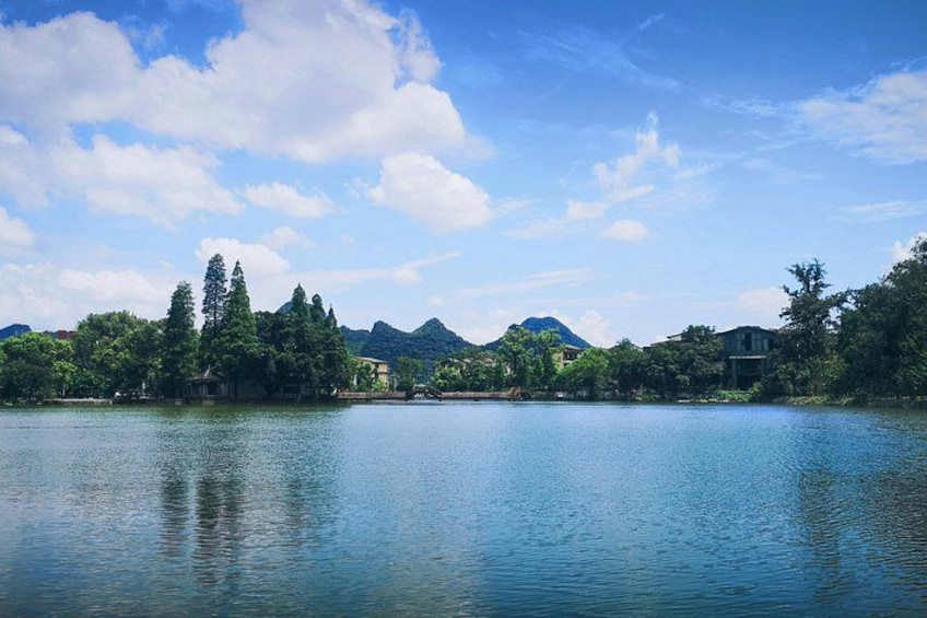 Ein ruhiger See mit Bergen im Hintergrund und Bäumen am Ufer. 2