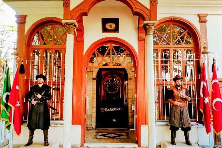 A building entrance with two guards, flags, and a decorative archway. 2