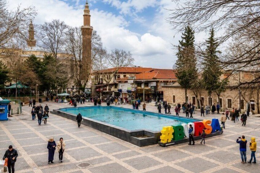 A public square with a pool, people walking, and a mosque with minarets in the background. 3