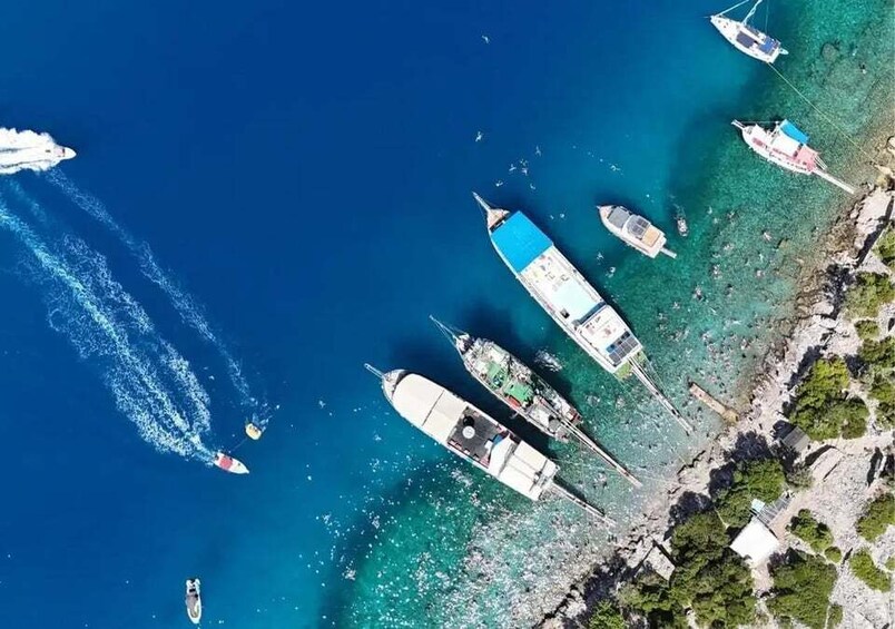 A coastal area with boats anchored near the shore, a jet ski in motion, and clear blue water. 5