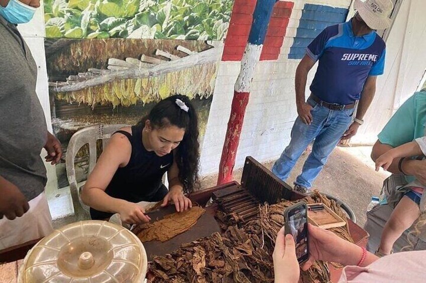 A person cutting dried plant material, likely for food preparation, with a large plastic container and a wooden cutting board. 1