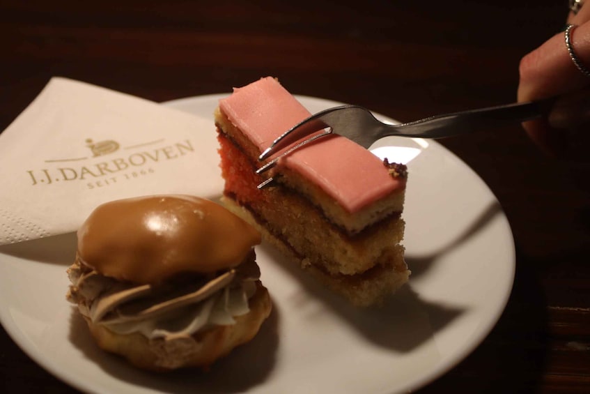 A dessert sandwich with a pink topping and a caramel bun on a white plate. 5