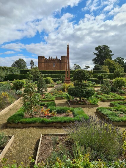A castle with a tall obelisk in a meticulously landscaped garden. 1