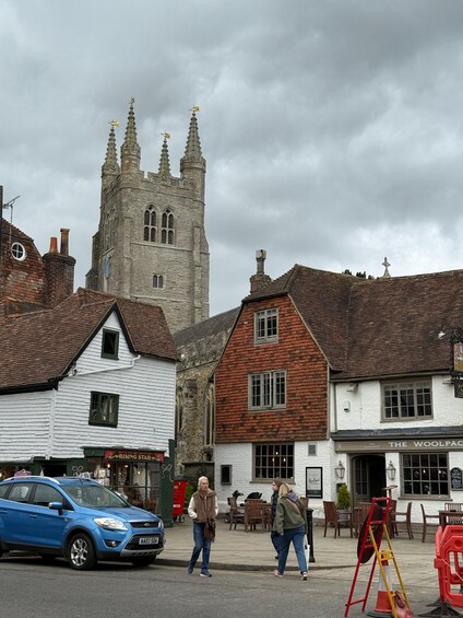 A historic church tower, a blue car, and a pub named 'The Woolpack.' 4