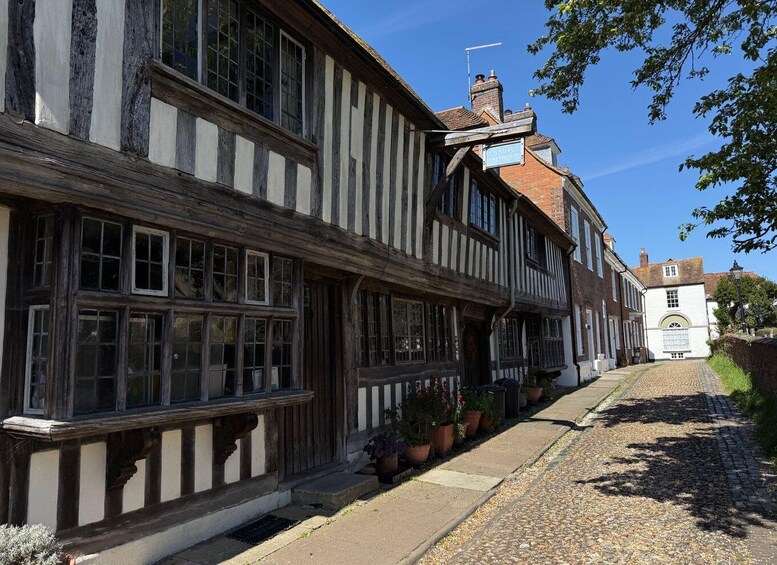 A traditional half-timbered building with a cobblestone street and a white building with a sign in the background. 2