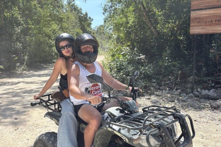 Dos personas en un cuatrimoto, un sendero de tierra y un letrero que dice 'PITAYA PRO'. 4