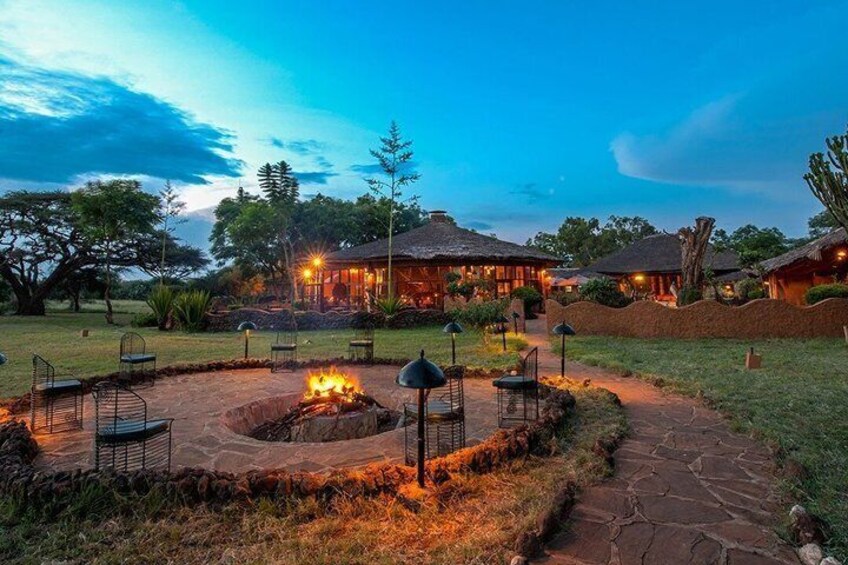 A lodge with thatched-roof buildings, a fire pit, and outdoor seating. 3