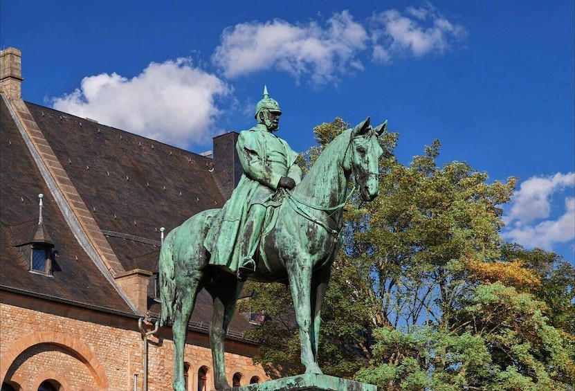 A statue of a man on horseback in front of a building with a sloped roof. 2