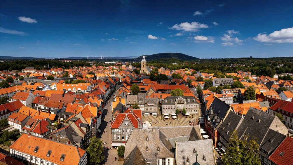 A town with red-roofed buildings, a central square, and a hill in the background. 4