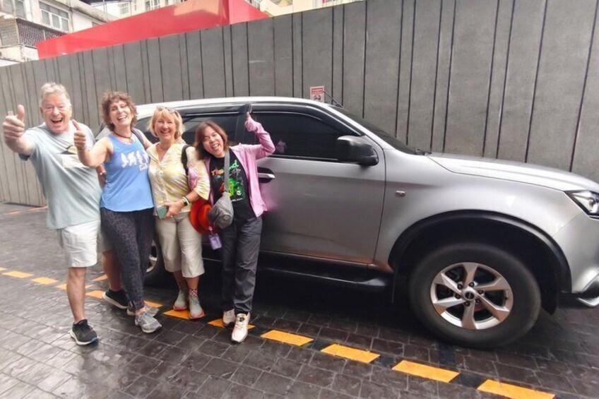 A group of people standing in front of a silver SUV. 2
