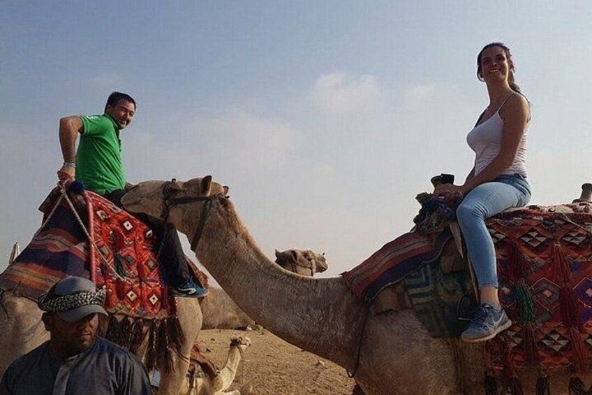 Two people riding a camel in a desert landscape. 4