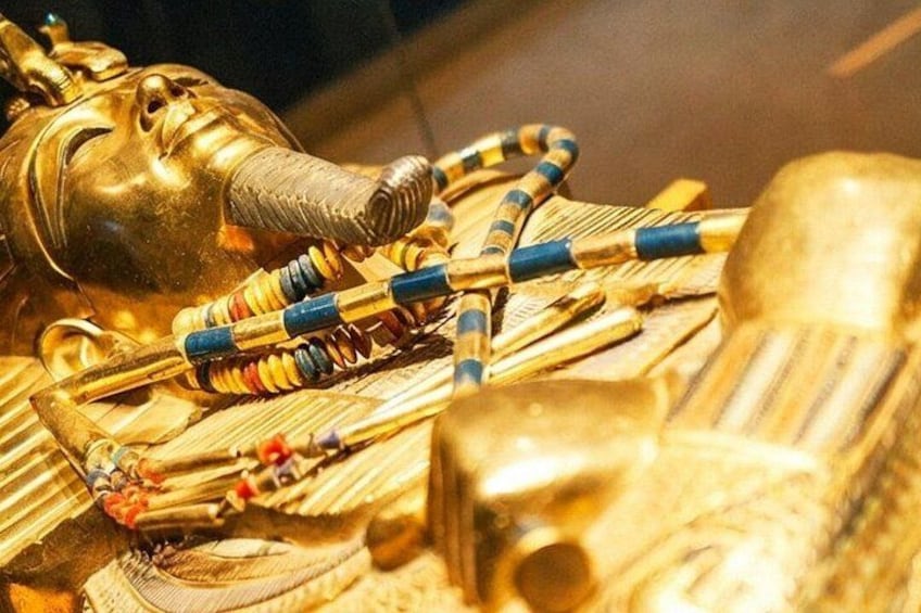 A golden sarcophagus with a cobra head, adorned with colorful beads and a blue and gold striped collar. 5