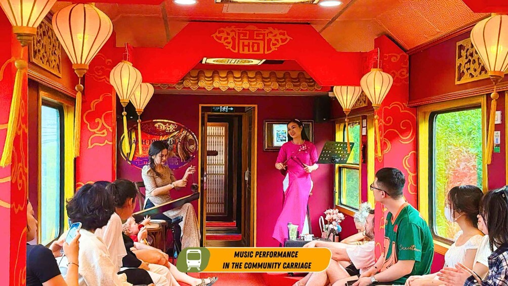 A music performance in a community carriage with red walls, traditional lanterns, and passengers seated. 3