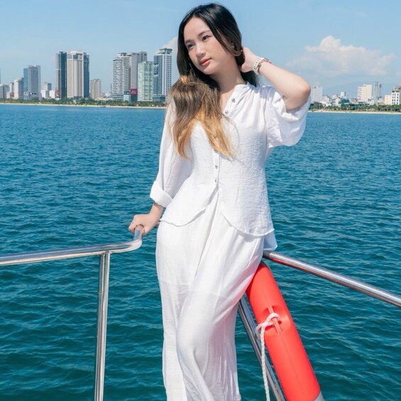 A person in white standing on a boat with a city skyline in the background. 5