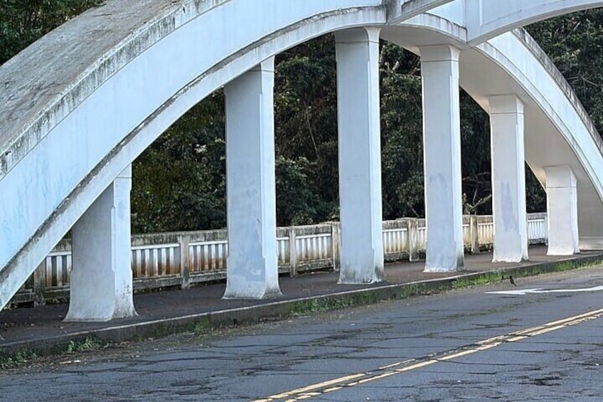A white bridge with multiple arches and columns, a road beneath, and a fence in the background. 4