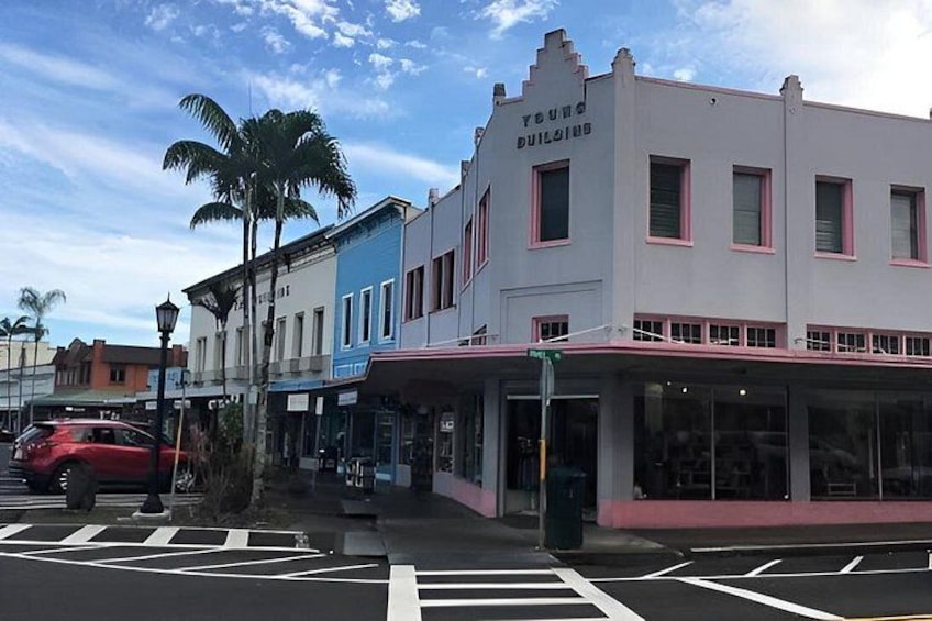 A street with buildings, palm trees, and a red car. 3