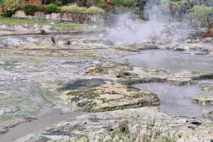 A geothermal area with mineral deposits and steam rising from the ground. 4