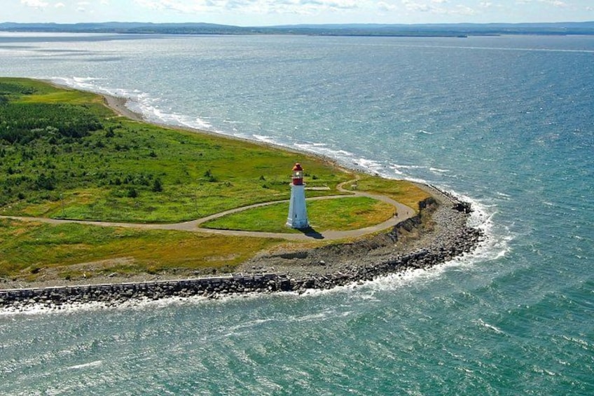 Un faro su uno sperone roccioso con una zona erbosa e vista sull'oceano. 2