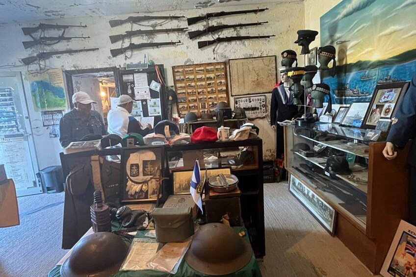 Una mostra museale con caschi militari, una mappa e diversi manufatti. 3