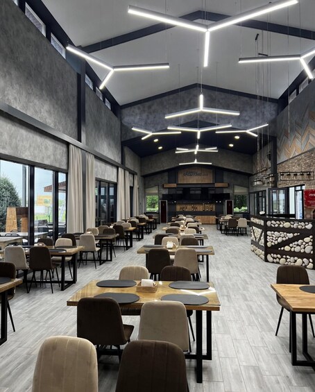 A spacious indoor dining area with modern lighting, tables, and chairs. 1