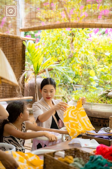 A person folding a yellow patterned fabric. 2
