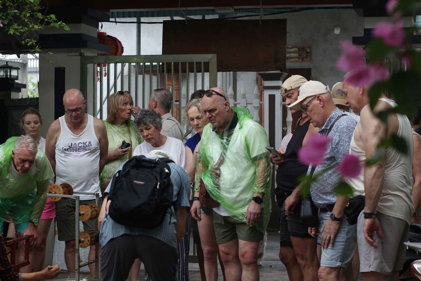 A group of people standing outdoors, some wearing green shirts, near a building with a metal gate. 5