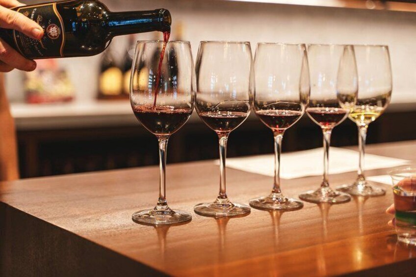 A person pouring wine into several glasses on a bar counter. 3