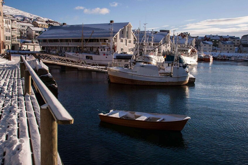 A harbor with boats, a wooden dock, and buildings in the background. 4
