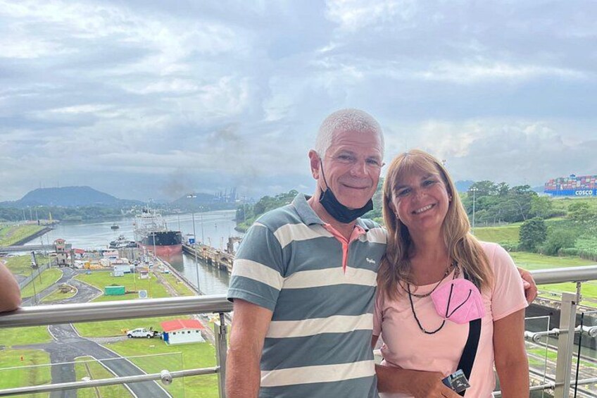 A man and a woman standing on a balcony with a view of a port and ships. 2