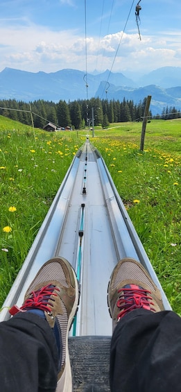 A person seated on a ski lift chair, looking down a snowy slope with mountains in the background. 3
