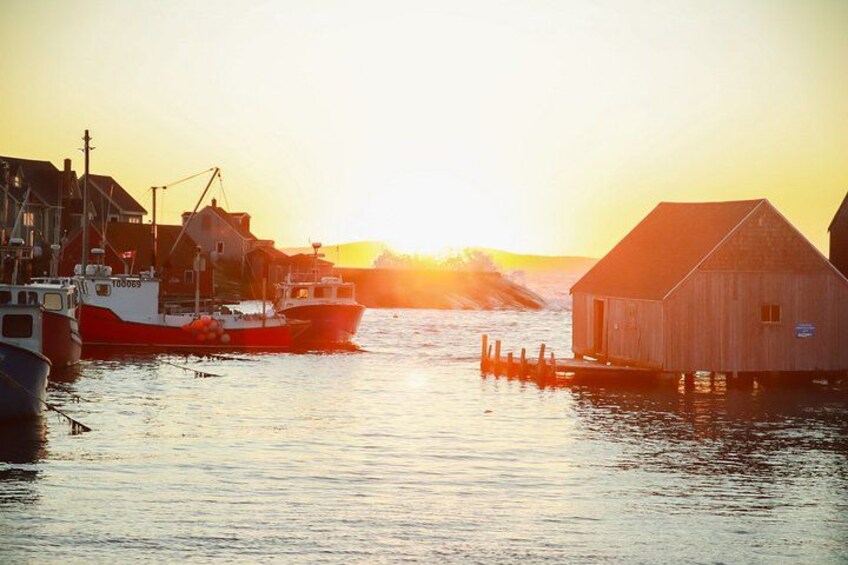 A harbor with boats, a wooden building, and a sunset. 2