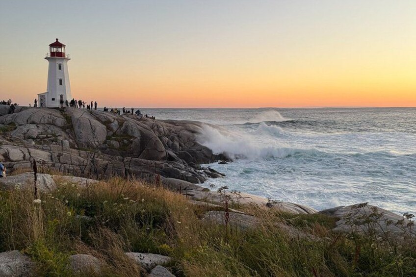 A lighthouse on rocky terrain, ocean waves, and a sunset sky. 4