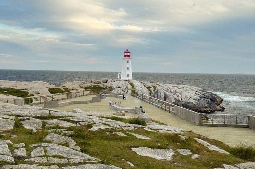 A lighthouse on rocky terrain with a wooden walkway leading to it. 4