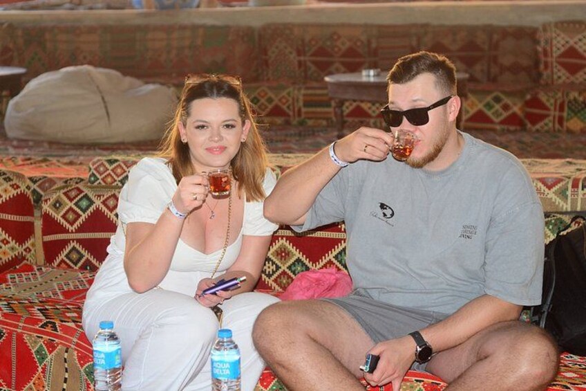 Two people sitting on a patterned couch with water bottles beside them. 3
