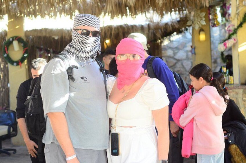 A group of people standing outdoors, some wearing casual clothing and head coverings. 2