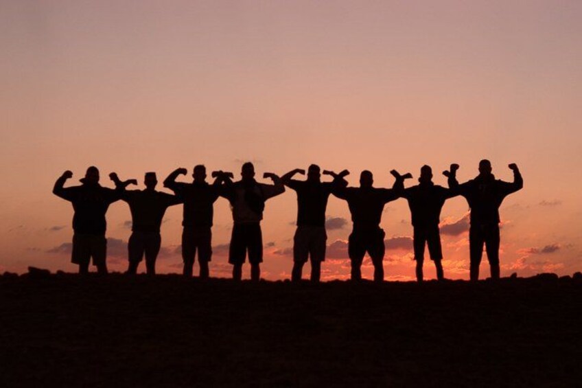 A group of people standing in silhouette against a sunset sky. 5