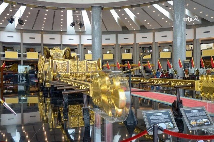 A grand hall with a golden throne, red carpet, and flags. 4