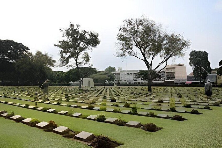 A cemetery with rows of graves, trees, and a small building in the background. 5