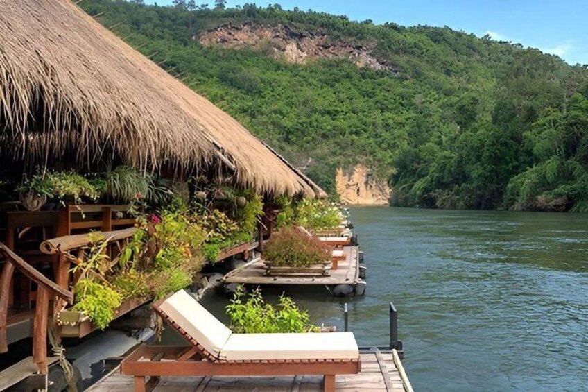 A riverside thatch-roofed structure with lounge chairs and planters. 3
