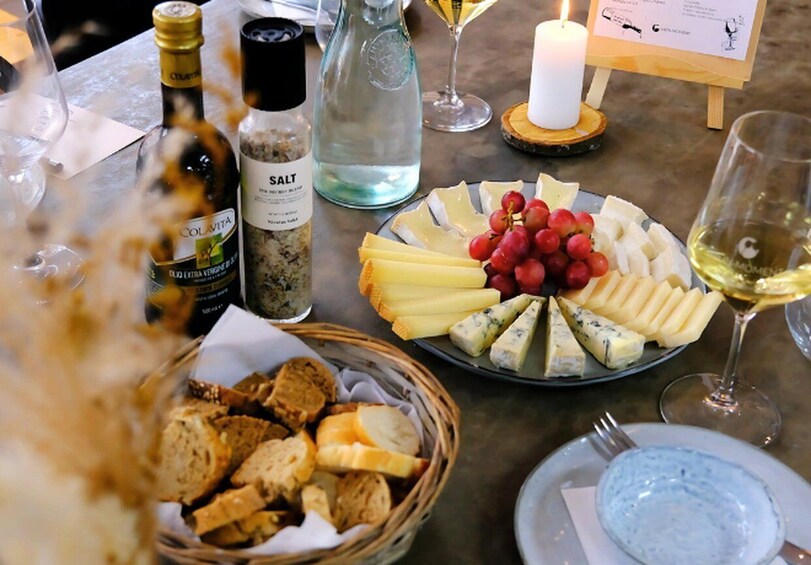 A cheese platter with various cheeses, grapes, and bread on a table. 1